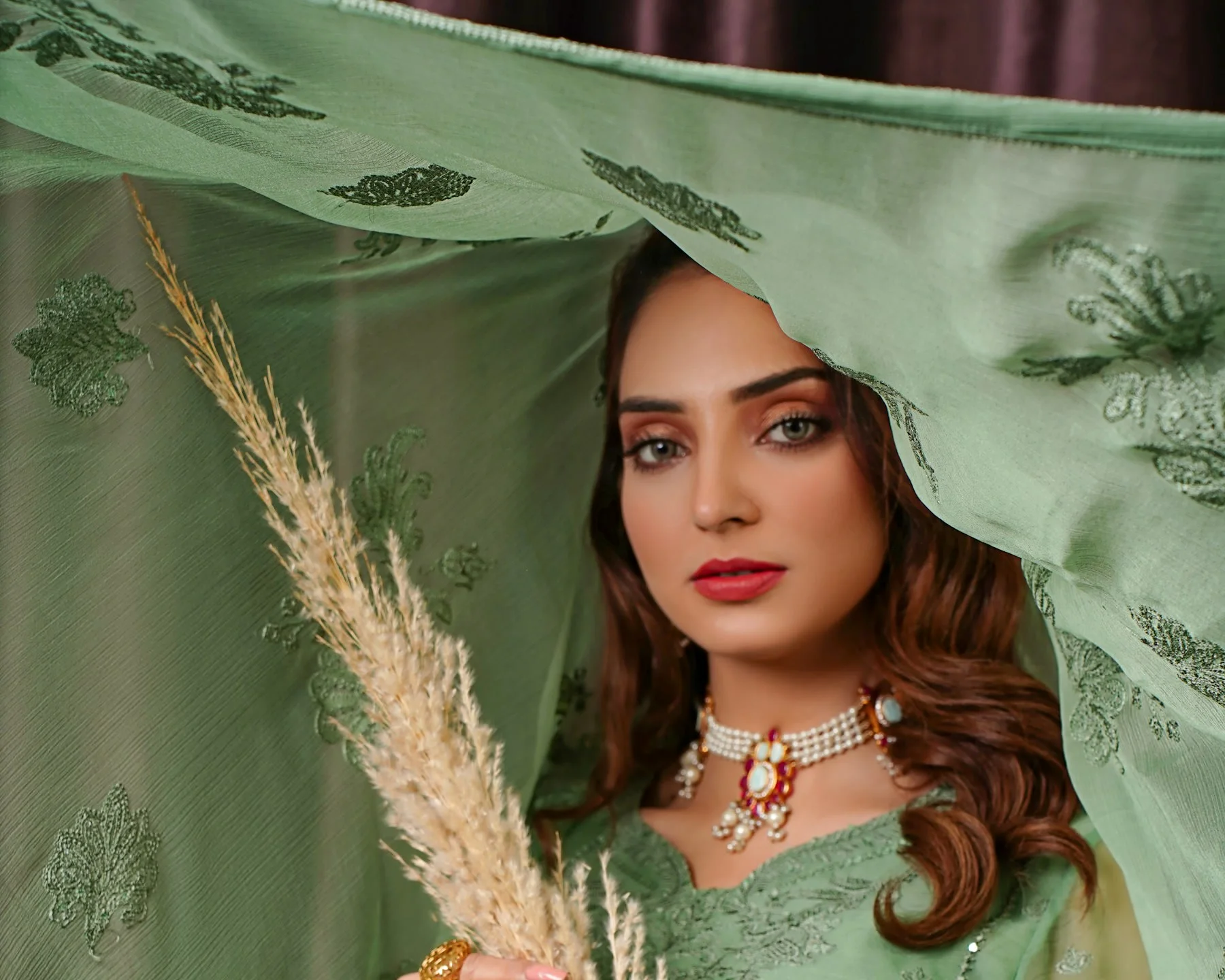 Woman in a sage green embroidered shalwar kameez with a matching dupatta